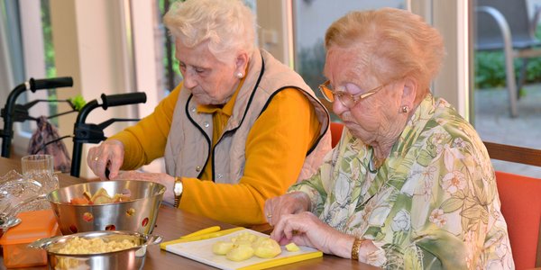 Zwei ältere Damen schälen gemeinsam Kartoffeln 