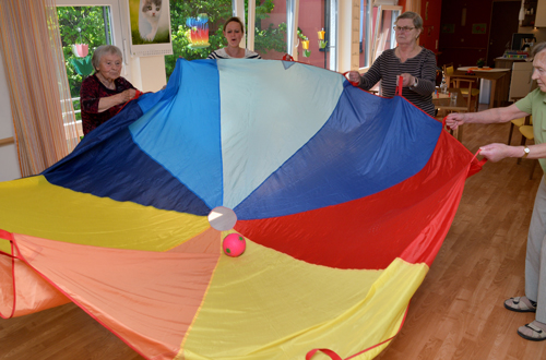 Bewohner spielen gemeinsam mit einem großen Tuch und Bällen
