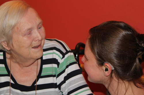 Eine Pflegerin unterhält sich liebevoll mit einer älteren Dame 